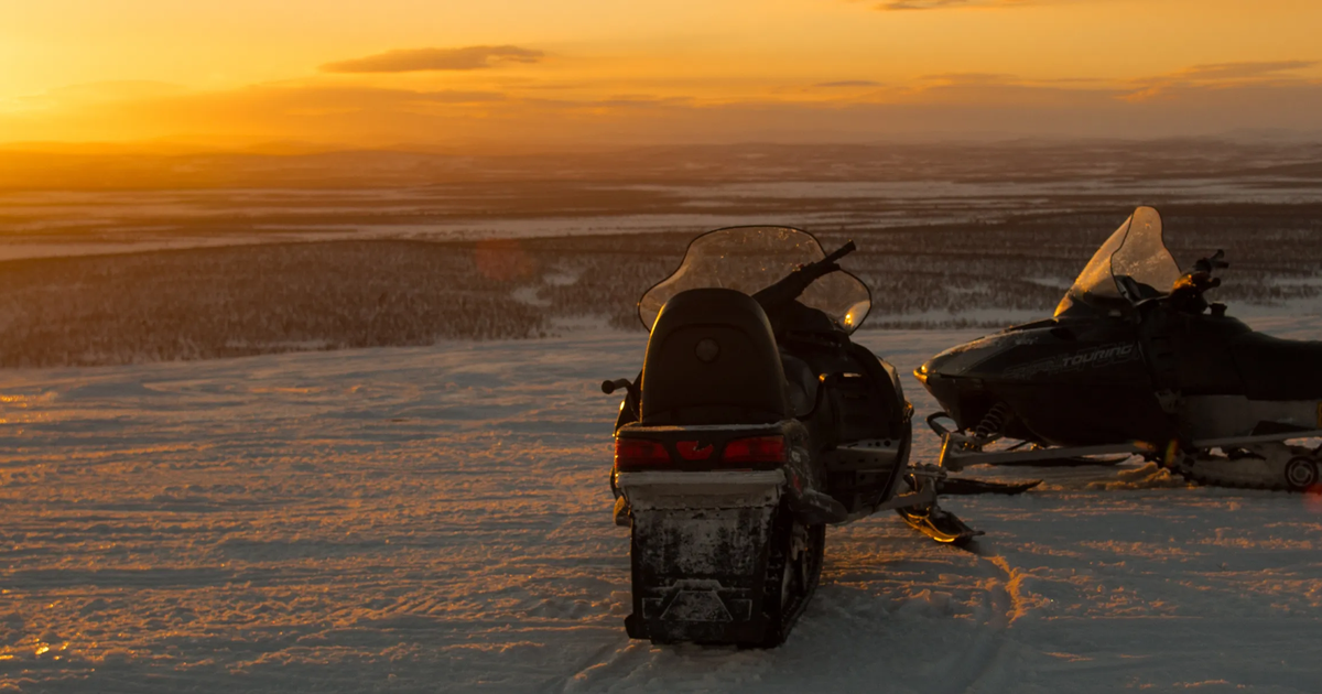 Snowmobile beneath the Northern Lights in Finnish Lapland